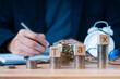 Man is writing on a paper and surrounded by coins and wooden blocks that spell out the word TAX