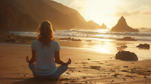 A Woman With Long Hair Sits On A Beach, Meditating, With A Large Rock In The Foreground And A White