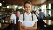 b'Portrait of a smiling waitress standing in a restaurant with arms crossed'