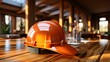 b'An orange hard hat sits on a wooden table in an empty room with wood beams in the ceiling.'