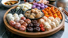 A Platter Of Tang Yuan Displaying Different Colored Doughs And Fillings Like Black Sesame Paste, Red Bean Paste, Or Peanut Butter