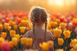 Back view of small girl child in field of tulip spring flowers.