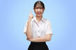 Portrait Asian student girl with Thai university uniform pointing finger isolated on blue background.