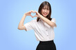Portrait Asian student girl with Thai university uniform making heart signal isolated on blue background.