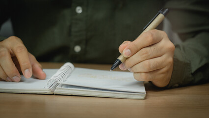 Wall Mural - businessman working at work table,home office desk background, checklist writing planning investigate enthusiastic concept. Male hand taking notes on the notepad.	