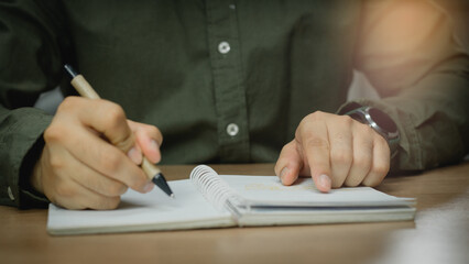 Wall Mural - businessman working at work table,home office desk background, checklist writing planning investigate enthusiastic concept. Male hand taking notes on the notepad.	