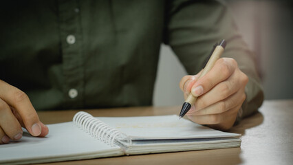 Wall Mural - businessman working at work table,home office desk background, checklist writing planning investigate enthusiastic concept. Male hand taking notes on the notepad.	