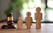 Wooden Figurine Family Positioned Beside a Judge's Gavel in a Courtroom - Legal Decisions, Family Law Concepts - Family Counseling, Social Services.