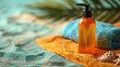 Bottle of a sunscreen and a colorful beach towel on a sandy beach