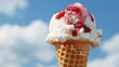 A vanilla ice cream cone with strawberry sauce against a blue sky