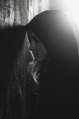 Canvas Print - A woman is standing in front of a wall, with her head down