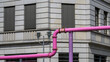 A pink pipe from a building site in front of a grey house wall