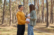 Cheerful pregnant couple husband and his wife resting in spring forest looking at each other with love enjoying nature and weekend spending together in woodland