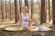 Training sport fertility. Caucasian expecting healthy pregnant woman doing yoga on mat sitting in woodland looking at camera enjoying active pregnancy and beautiful nature