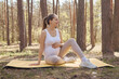 Female abdomen fitness. Body motherhood gymnastic. Yoga exercise beauty during pregnancy. Caucasian pregnant woman doing yoga on mat in summer forest