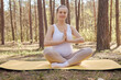 Meditating recreation outside. Abdomen fitness relaxing. Caucasian pregnant woman doing yoga on mat sitting in lotus pose with praying gesture exercise beauty body