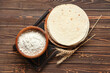 Tasty lavash and bowl with flour on wooden background