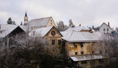 Wall Mural - A snowy December day in Skofja Loka in Gorenjska, Slovenia. The north shore of the Selska Sora river as it flows through the historic centre