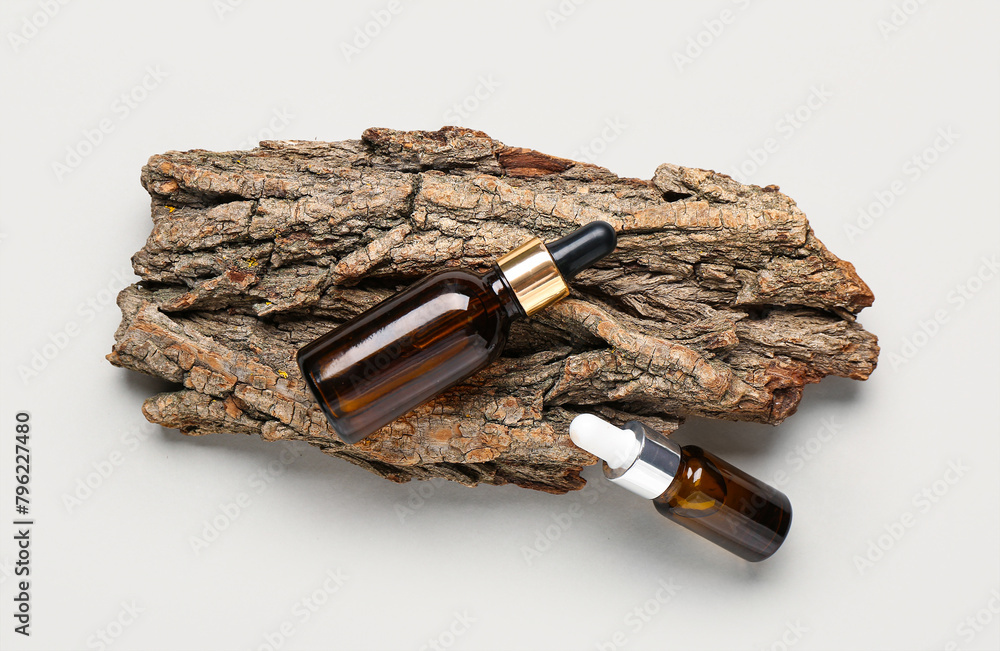Tree bark and bottles of essential oil on white background, closeup