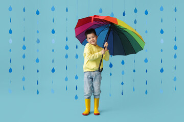 Sticker - Cute little Asian boy in gumboots with umbrella and paper raindrops on blue background