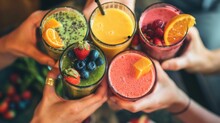 Hands Holding Glasses Filled With Nutrient-packed Fruit Smoothies, Showcasing A Healthy Lifestyle
