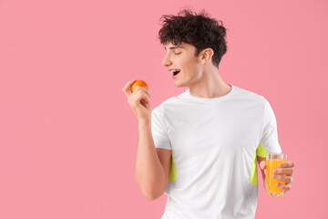 Poster - Handsome young happy sporty man with glass of juice and orange on pink background. Weight loss concept