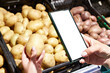 Potato vegetable in hand and smartphone