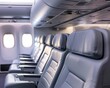 © ItziesDesign - Perspective shot of a row of airplane seats with overhead compartments, emphasizing comfort and design in modern air travel interiors