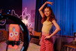Medium long shot of cheerful teen girl with long red hair recording dance video for social media platform, copy space