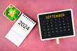 Calendar for September 2024 in black chalkboard on red background.
