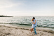 Man and woman standing on sand sea. Female and male kisses on beach ocean and enjoying sunny summer day. Couple in love hugging and kissing each other on seashore. Side view. Spending time together