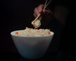 Hand Holding Chopsticks With Rice and Vegetables on Dark Background