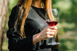 Beautiful girl holding glass of wine at summer backyard party. Woman's hand holds glass of champagne close in garden. tasting red wine. Woman drinking wine in park. Friends and summer concept.