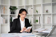 Asian female accountant Use a calculator to calculate business numbers on a white wooden table in the office.