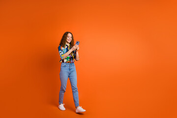 Poster - Photo of lovely cheerful girl dressed trendy clothes typing texting going empty space isolated on orange color background