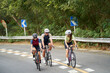 group of three young asian people riding bicycle outdoors on rural road