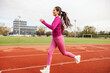 A fit sportswoman running on running track at stadium.