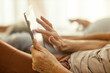 Close up of senior woman's hands scrolling on tablet in bedroom.