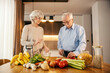 A happy senior couple is making lunch together at home.