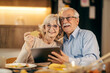 Portrait of a senior couple using tablet and credit card for online shopping at home.