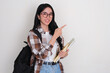 © KrishnaTedjo - Female college student holding books smiling and pointing beside her