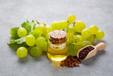 Fototapeta Dinusie - Grape seed oil in small bottle and bunch of grapes together.