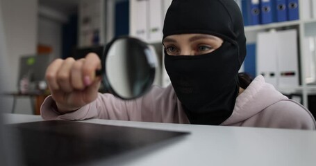 Man in balaclava looking at laptop screen with magnifying glass 4k movie. Internet fraud concept