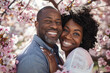A happy African American couple smiling and embracing under a cherry blossom tree