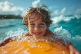 Fototapeta Tęcza - portrait of a happy child having fun on a bodyboard in the waves on a summer holiday