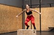 Strong woman jumping on box in a cross training gym