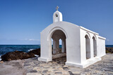 Fototapeta  - A white Orthodox chapel on a stone headland in the town of Georgioupoli on the island of Crete