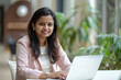 © AI_images - Successful Indian woman working on a laptop in a bright office space, demonstrating success and positivity.