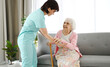 © Ievgen Skrypko - Nurse Hands Cane To Elderly Woman And Helps Her Move Around The Room In A Nursing Home
