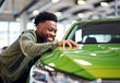© ProstoSvet - Delighted man showcasing pride for his new car at a vehicle showroom.